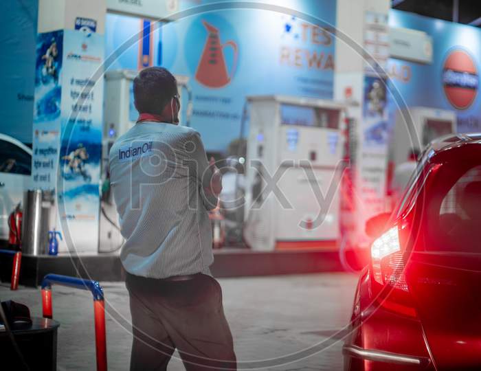 Pump Boy Completing Filling Petrol At An Indian Oil Petrol Pump In A Waiting Car With Lights On Closing The Fuel Cap While Other Cars Move In To Get Fuel Filled