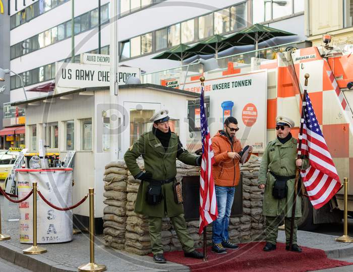 Tourist Taking Photos At Checkpoint Charlie, Cold War Spot In Berlin, Germany