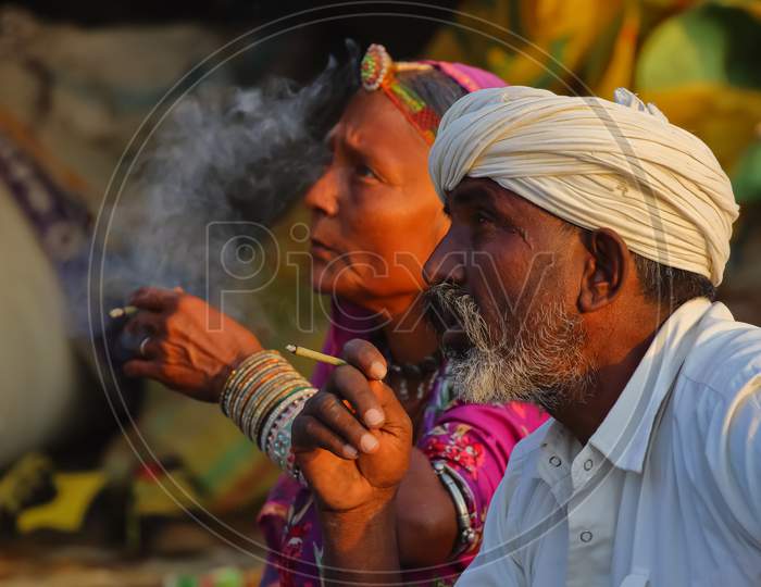 A tribal man and women siting and smoking local Indian cigar