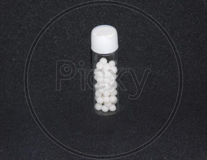 Closeup Of A Medicine Bottle With Capsules Isolated On Black Background