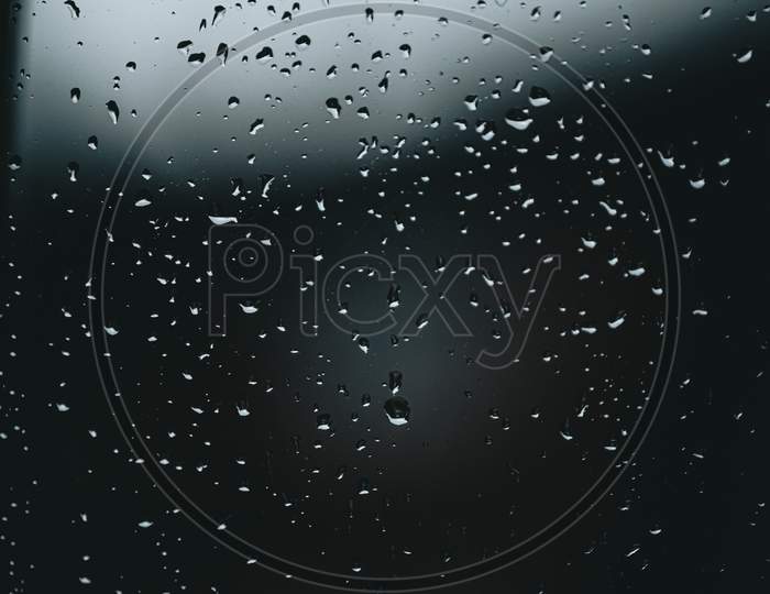 Horizontal Background Of Some Moody Rain Drops Over A Window With Dark Tones And Textured Droplets