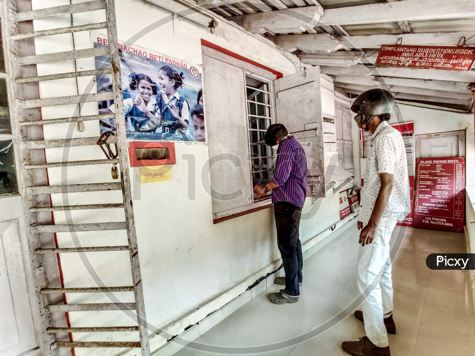 Vythiri, Kerala / India - 09.31.2020 : Landscape View Of Two Young Indian Men Wearing Masks And Maintaining Social Distance In Post Office Due Corona Virus Or Covid 19 Pandemic.
