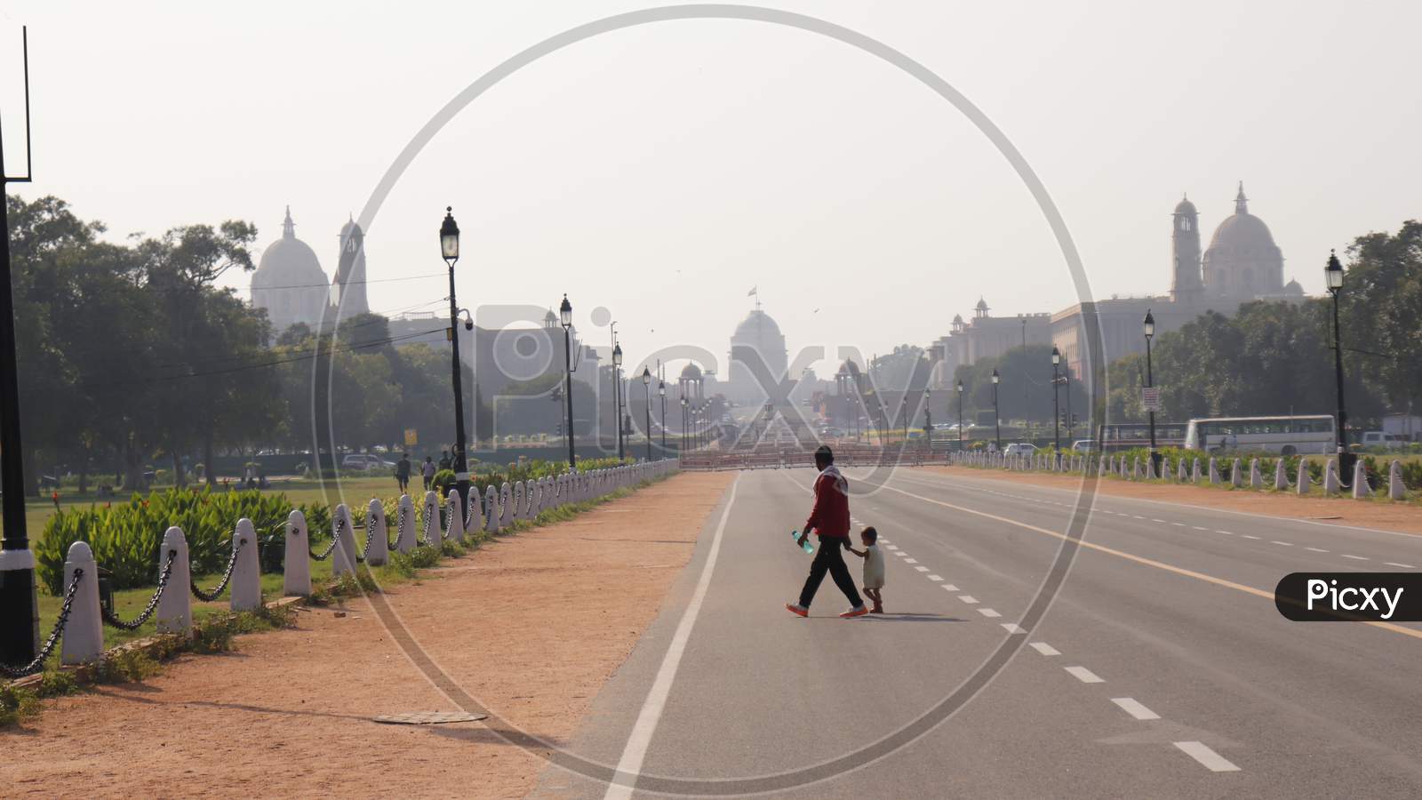 FATHER AND SON CROSSING ROAD IN FRONT OF RASHTRAPATI BHAVAN DELHI, INDIA OCTOBER 2ND 2020