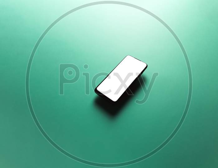 Minimalistic Mock Up Flat Image Design With A Floating Mobile Phone With Copy Space And White Scree To Write Over It Over A Flat Green Background