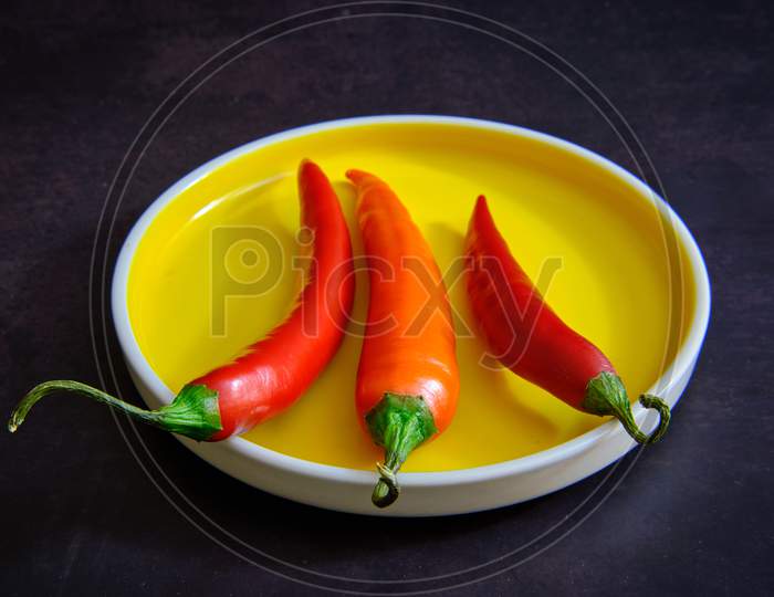 Red Chilli Pepper On Yellow Plate In Dark Background