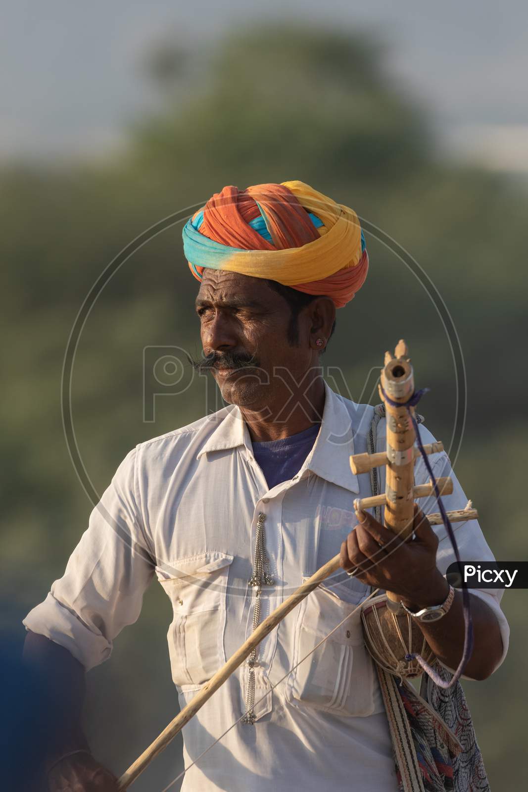 A man dressed in traditional rajasthani clothes playing musical instrument violin