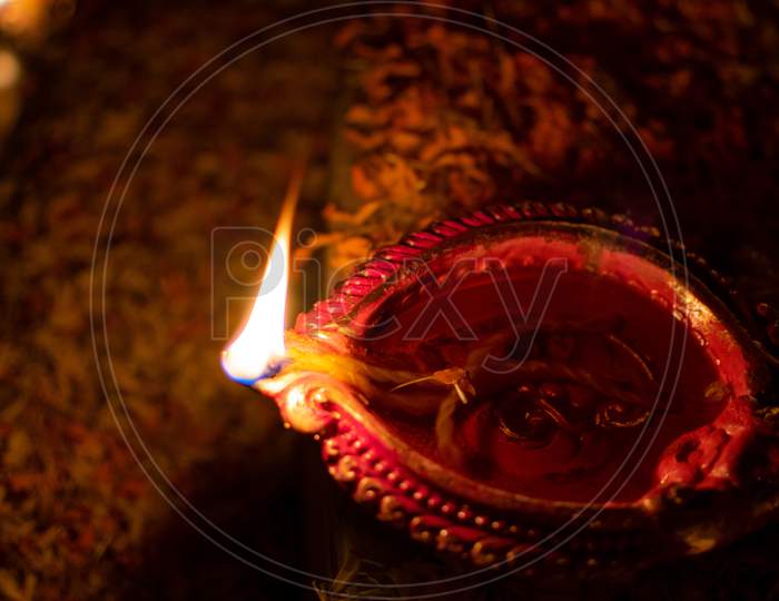 Close up image of Diya oil lamp with fire on dark background. Traditional Diwali festival