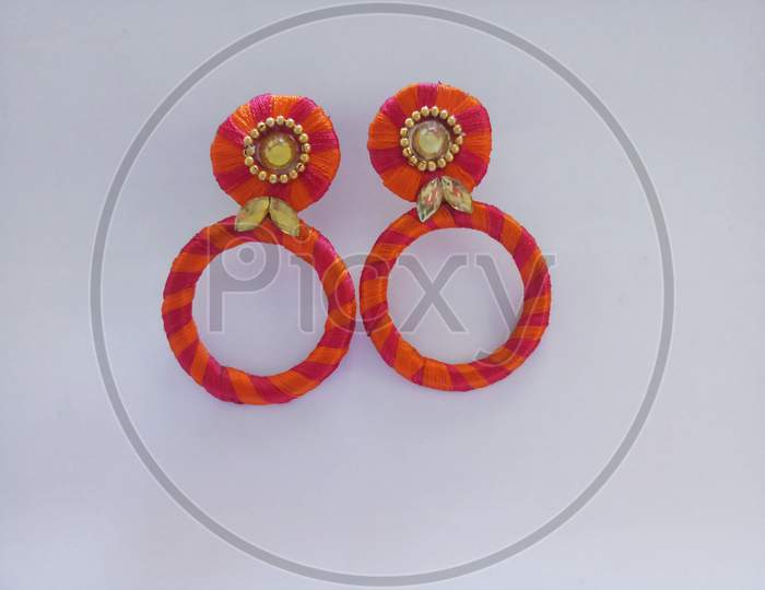 orange color home made earrings in a white background