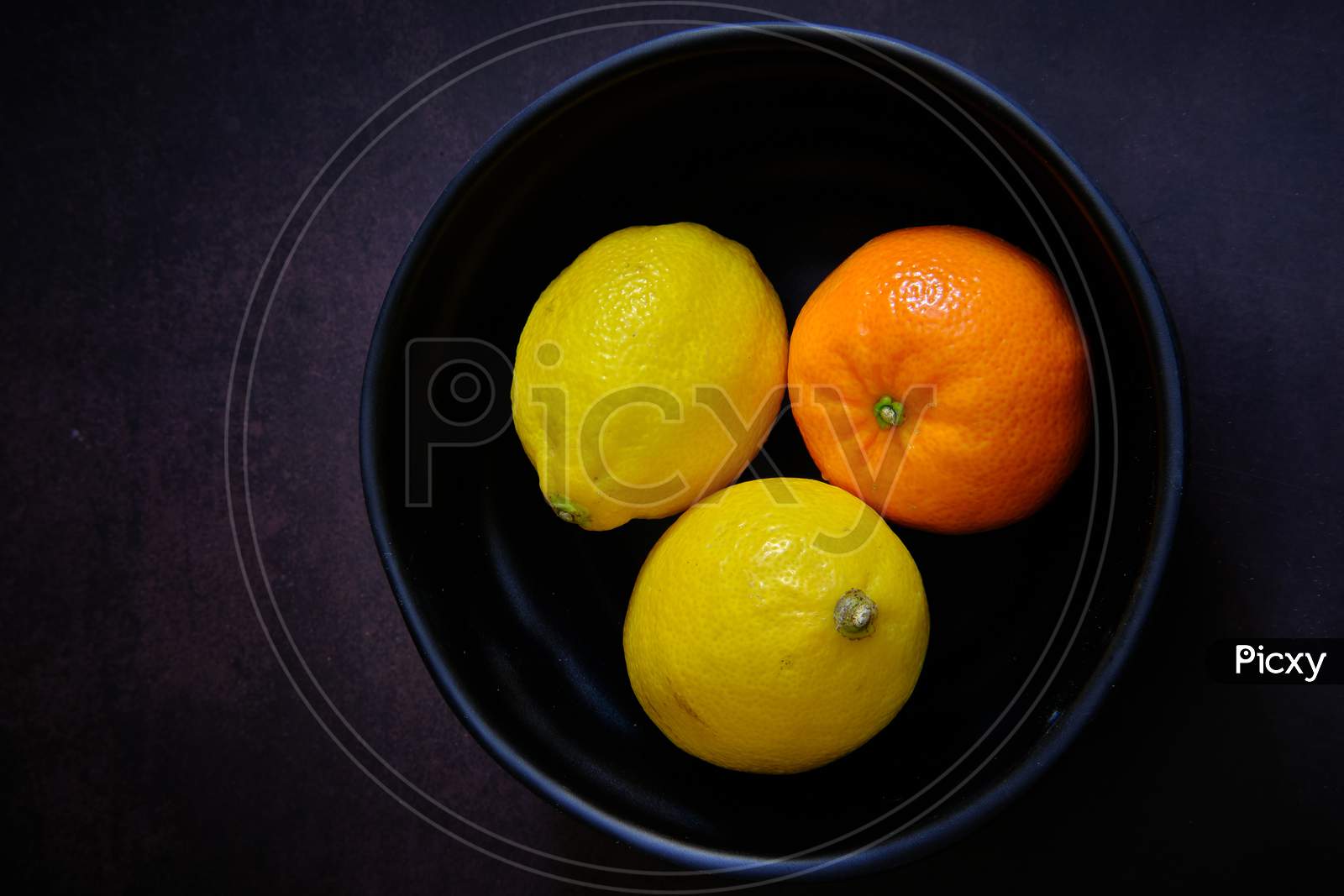 Lemon And Orange On Black Bowl In Dark Background
