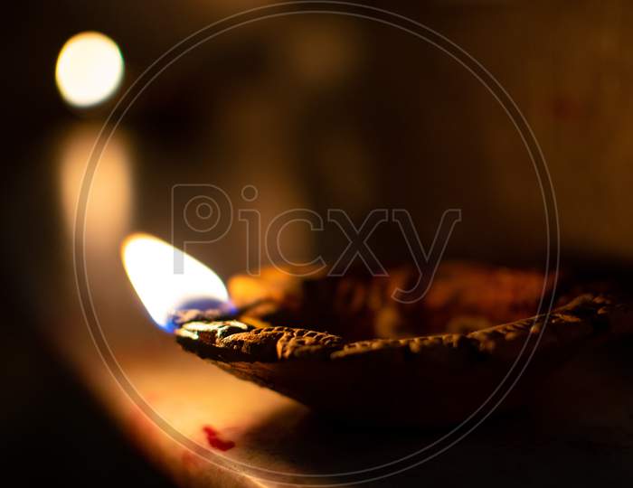 Close up image of Diya oil lamp with fire on dark background. Traditional Diwali festival