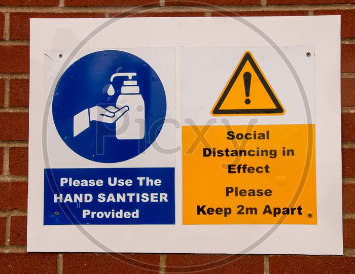 New Normal Warning Signs. Social Distancing Keep 2M Apart In Yellow And Use Hand Santiser Provided In Blue. Norfolk, UK - October 4th 2020