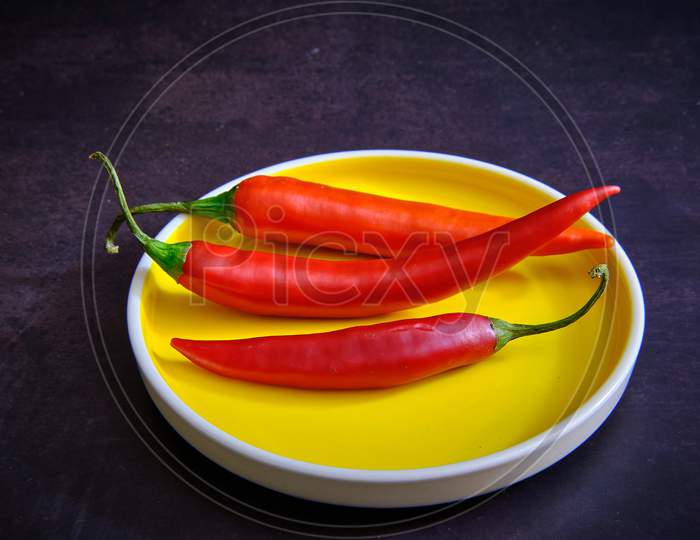 Red Chilli Pepper On Yellow Plate In Dark Background