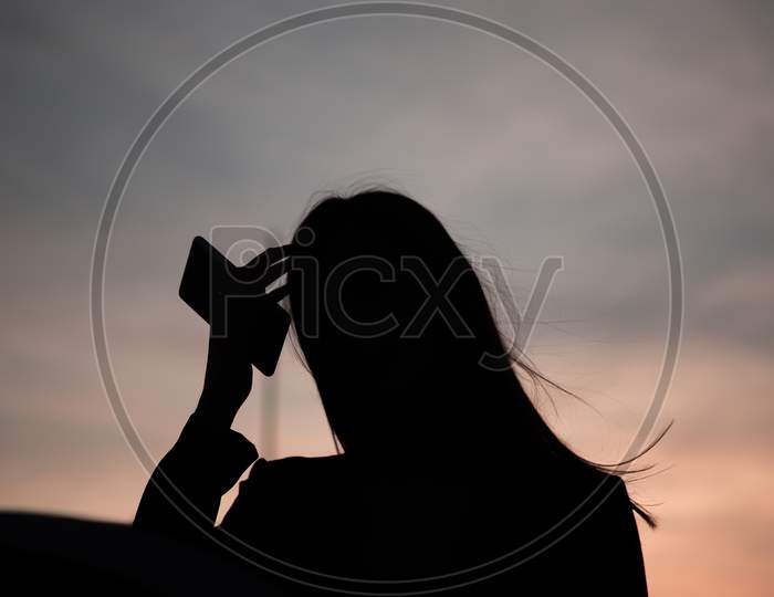 A Silhouette Of A Beautiful Young Woman At Sunset