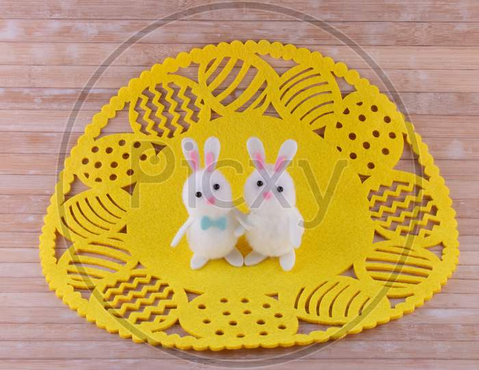 Cute Easter Bunny Couple Hugging On Bright Yellow Easter Egg Doily On Wooden Background