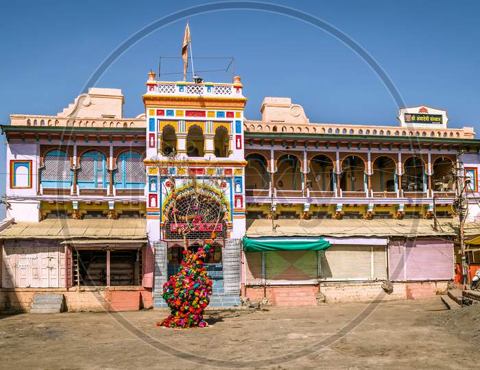Brightly colored , freshly painted goddess Ambadevi temple with worshiping tree in Amravati, Maharashtra. Translation in English, of the text written on boards in local language is the temple name.