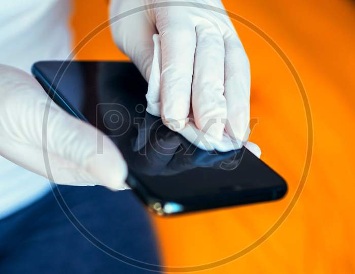 Women Clean Cell Phone With Glove For Corona Virus