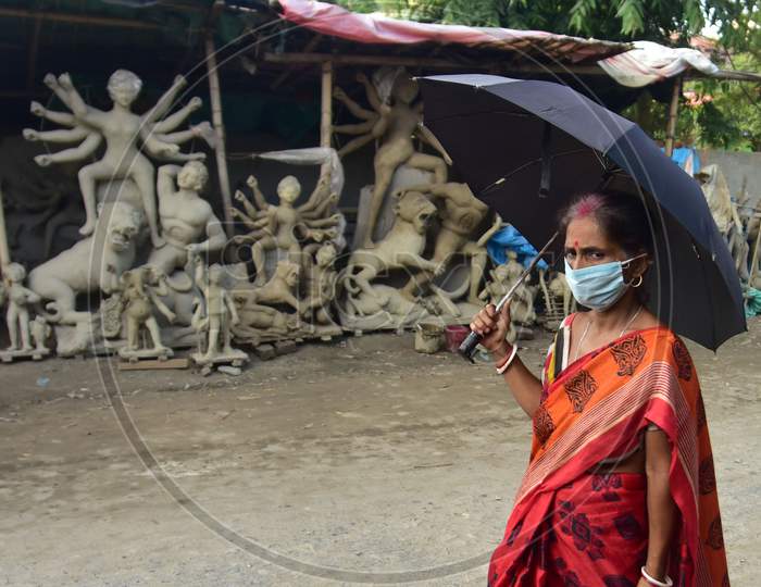 A Women walks past  near an  incomplete Hindu God Durga idol on a roadside area in Nagaon District of Assam on  Oct 9,2020.