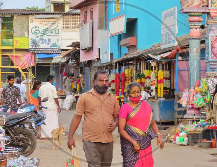 A Man And A Woman Walk Together In The Market Wearing Masks To Protect Themselves From The Corona