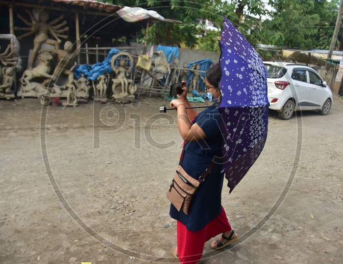 A Women clicks a photo of an incomplete Hindu God Durga idol on a roadside area in Nagaon District of Assam on  Oct 9,2020.