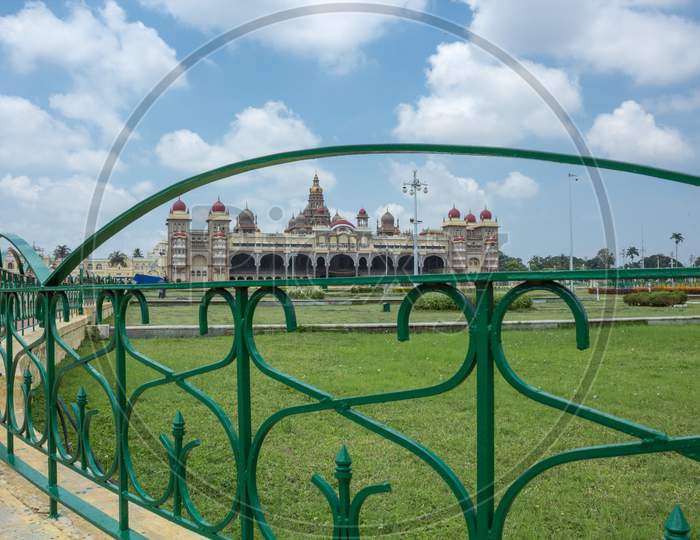 A Beautiful view of the Ambavilas Palace with the Clouds seen through the garden railing in Mysuru cityscape of Karnataka/India.