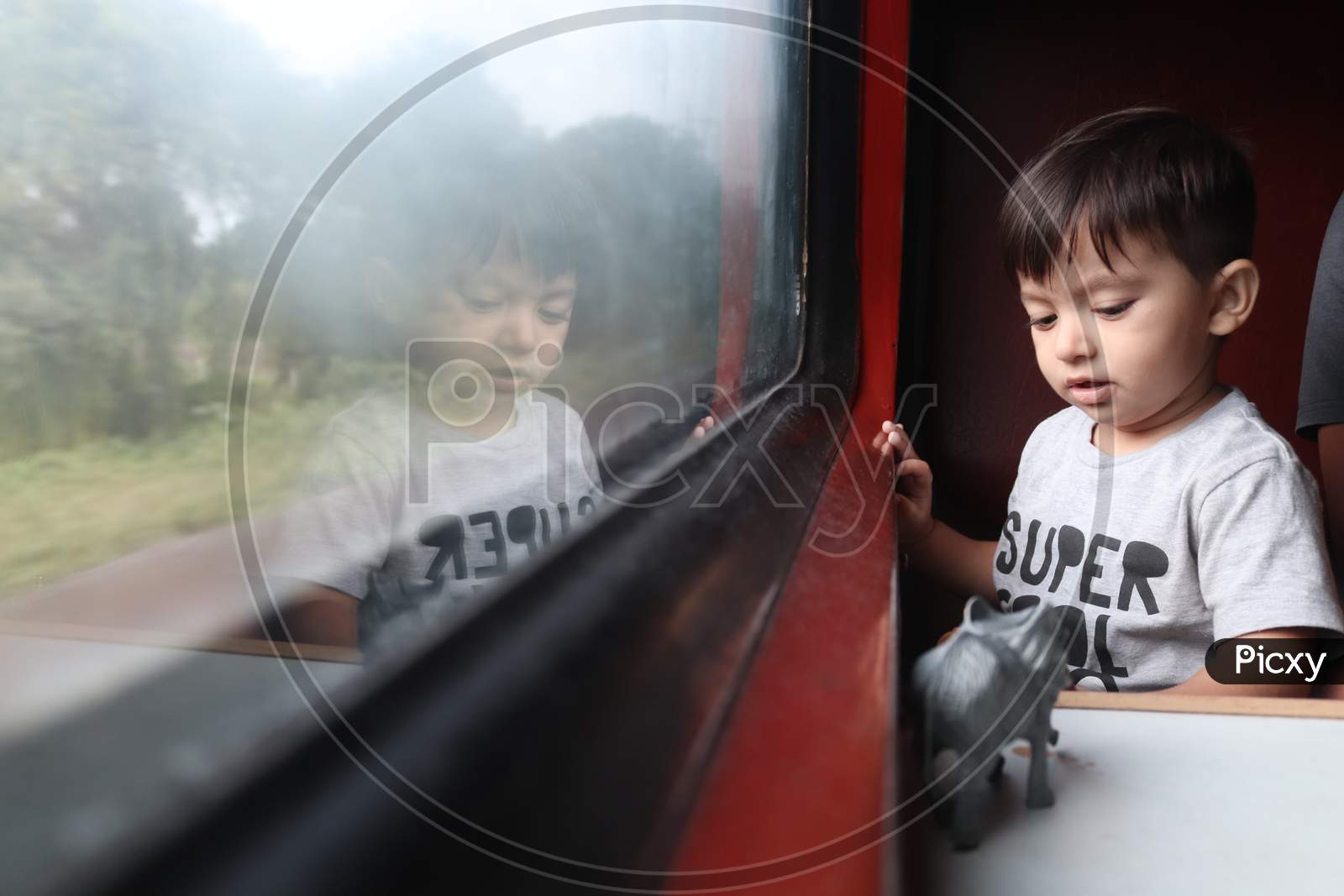 young indian cute baby boy sitting at window seat and playing