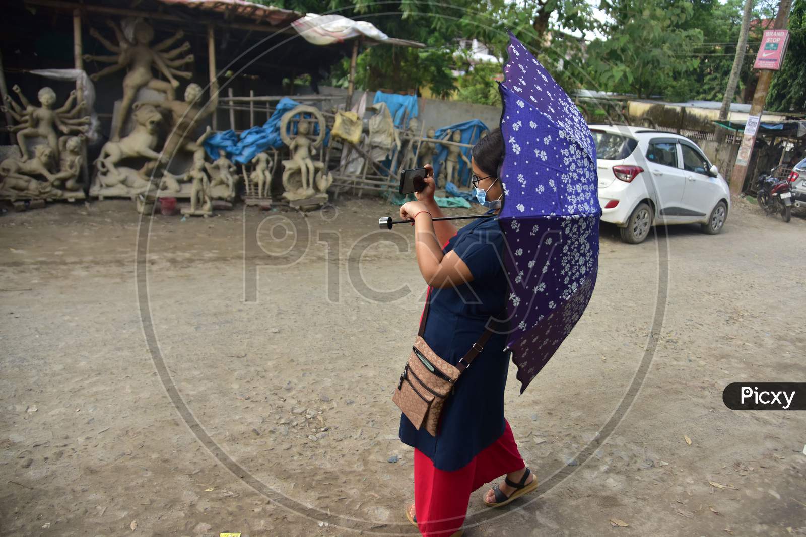 A Women clicks a photo of an incomplete Hindu God Durga idol on a roadside area in Nagaon District of Assam on  Oct 9,2020.