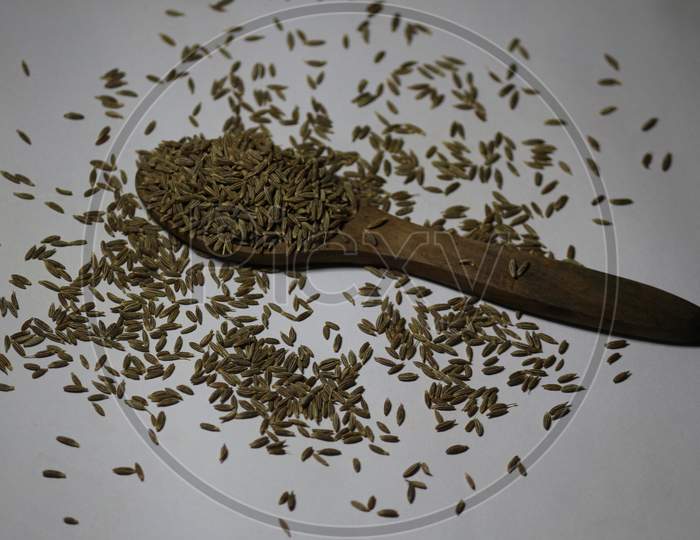 A closeup spoon of full of healthy tasty beneficial cumin seeds on white background