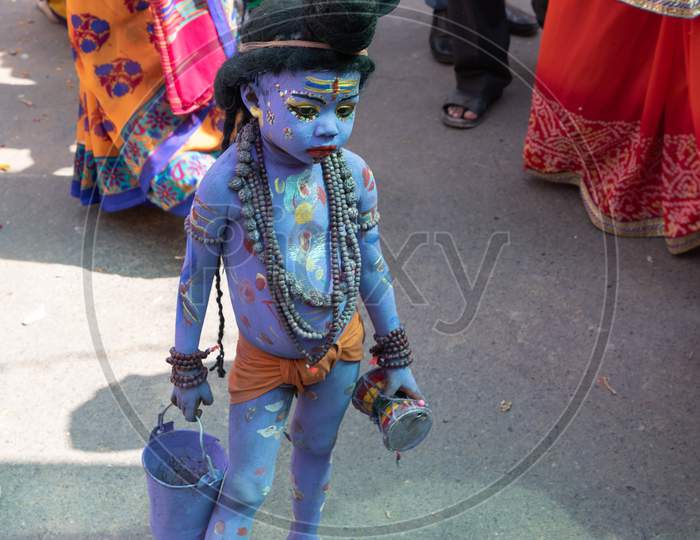 A little boy with his body painted blue to depict hindu god Shive on the streets