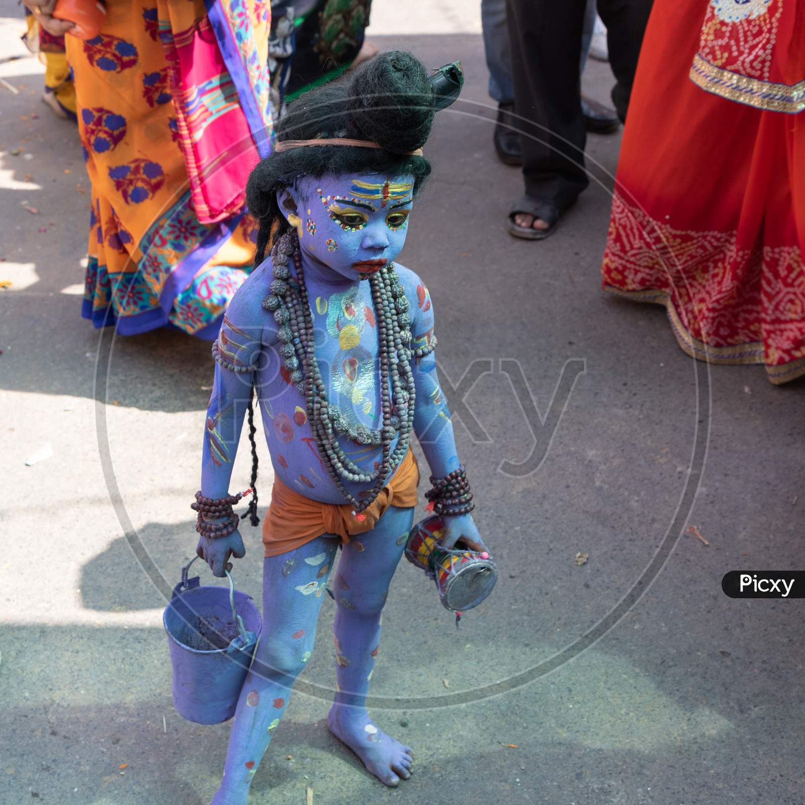 A little boy with his body painted blue to depict hindu god Shive on the streets