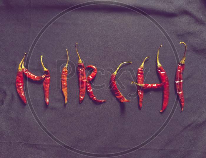 Red chilies with black background likes written "Mirchi" in Hindi.