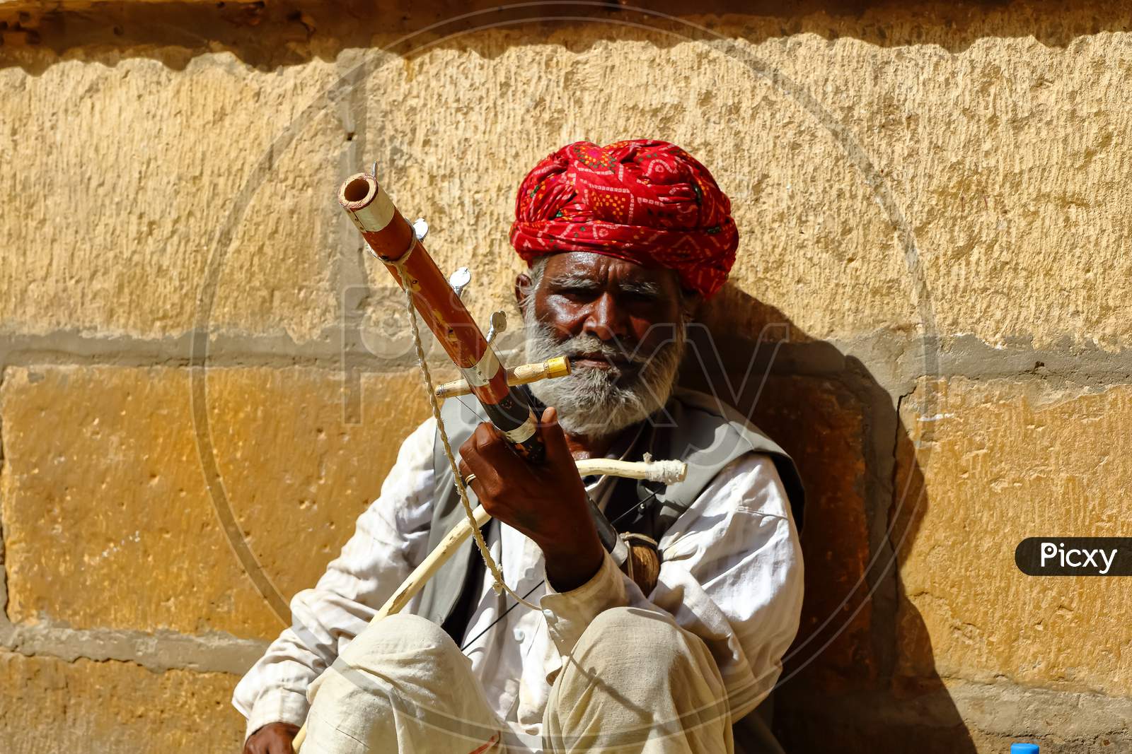 A man wearing turban is siting on ground and playing vilolin at Jaiselmer Rajasthan