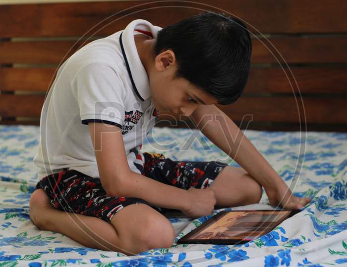 Kid watching movie on Tablet pc. Kid playing on tablet pc. Kid at home during lock down