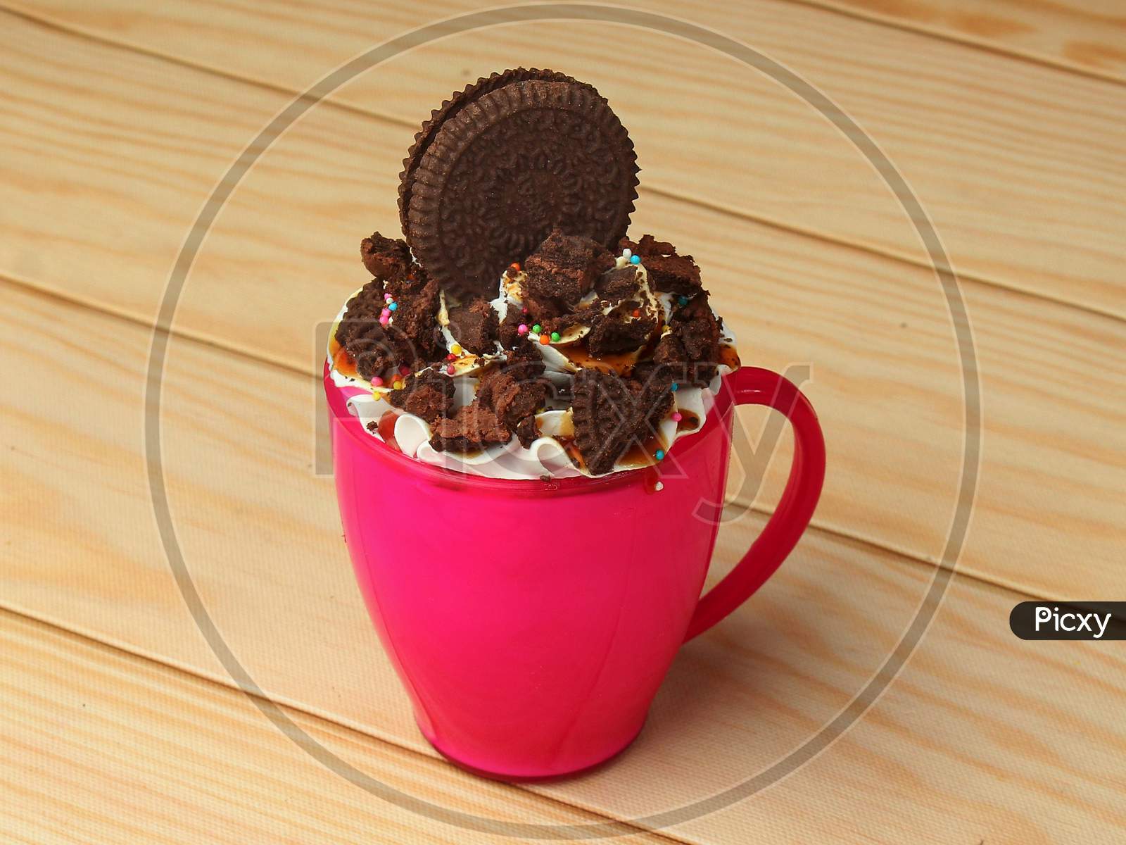 Oreo Biscuit Mug Cake With Colorful Sprinkles On Wooden Background