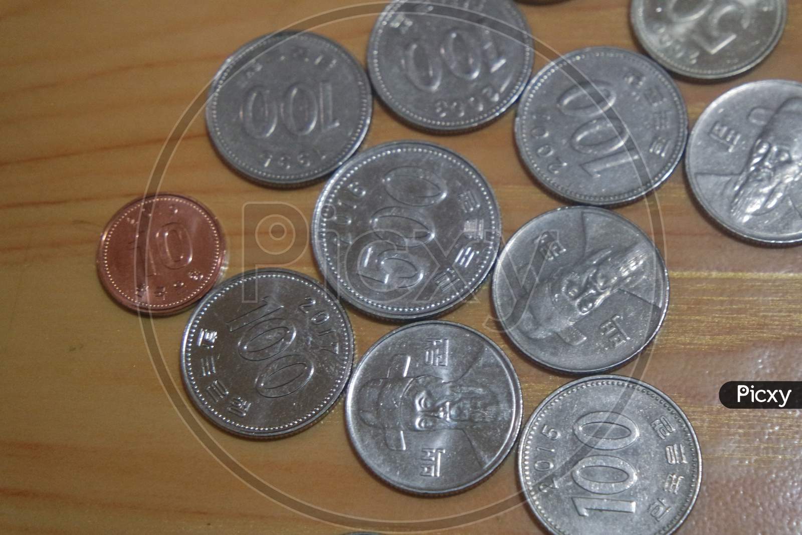 Korean Won Coin Scattered Over A Wooden Floor