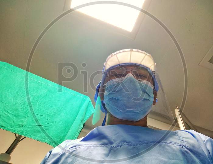 Surgeon in scrub and face shield