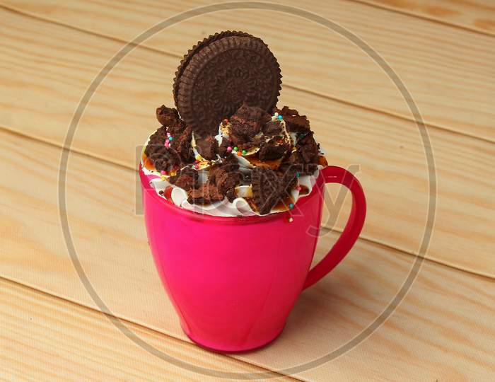 Oreo Biscuit Mug Cake With Colorful Sprinkles On Wooden Background