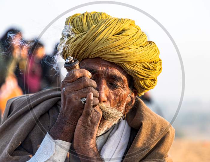 A Rajasthani Tribal Man Smoking Chillam At Pushkjar Camel Festival.