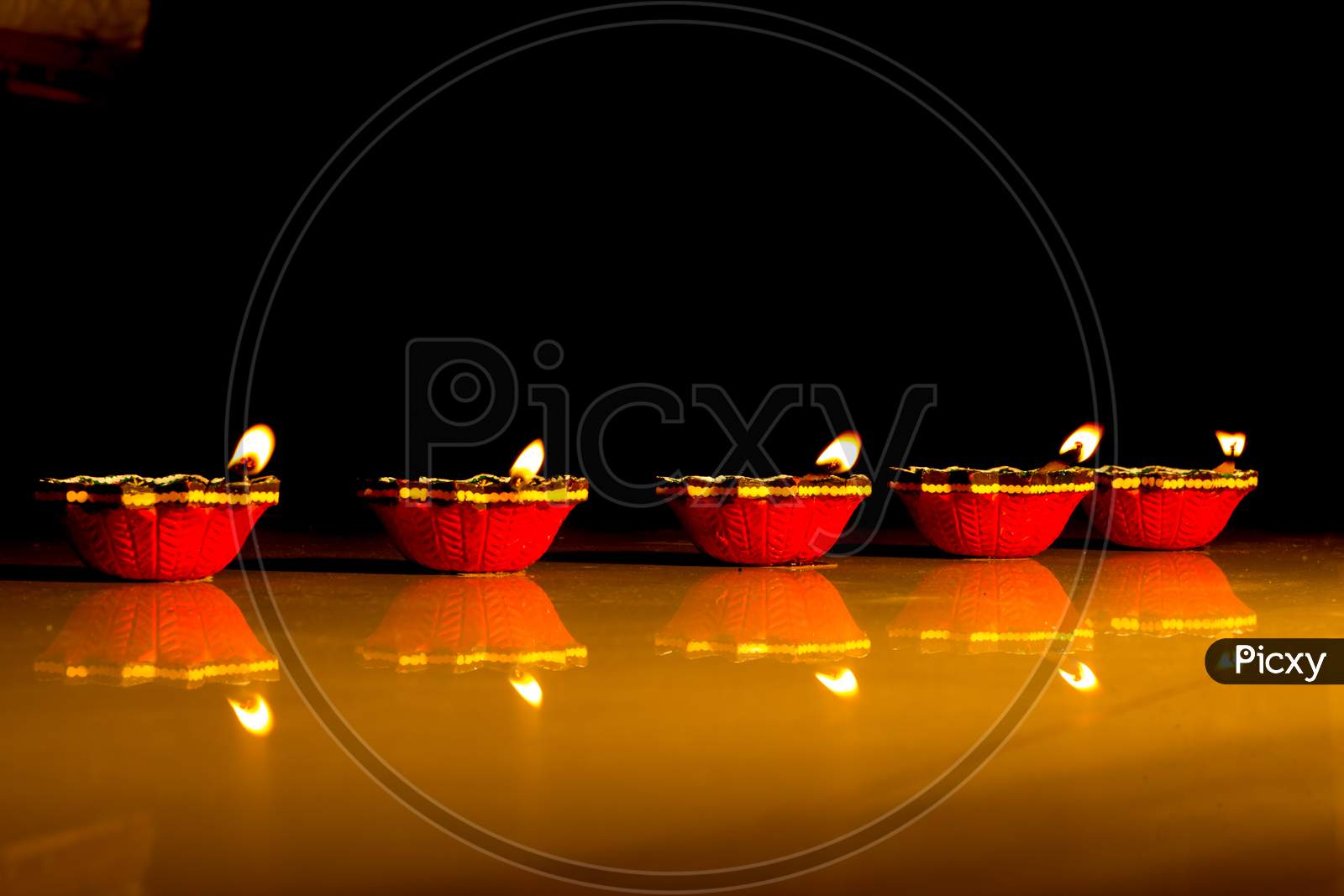 A Dramatic view of traditional Earthen lamps lit with oil and Wicks against dark background for the Diwali festival of Lights which is Celebrated across India.