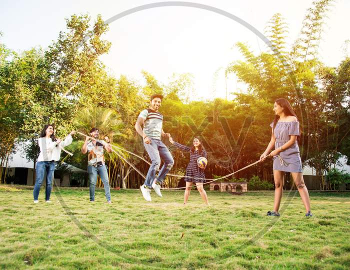Indian Asian Young Friends Playing Jumping Rope, Enjoying Recreational Skipping Rope Game Outdoors