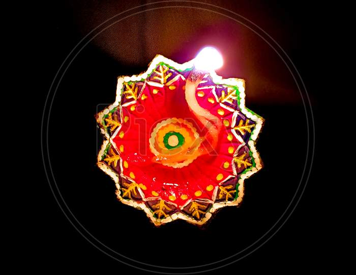 A Divine Top view of an Handmade Earthen lamp lit with traditional oil or ghee against a dark background  for the Deepavali festival celebrated across the Indian States.