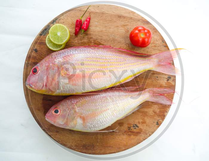 Fresh Pink Perch Fish Decorated With Curry Leaves On A Wooden Pad,White Background.