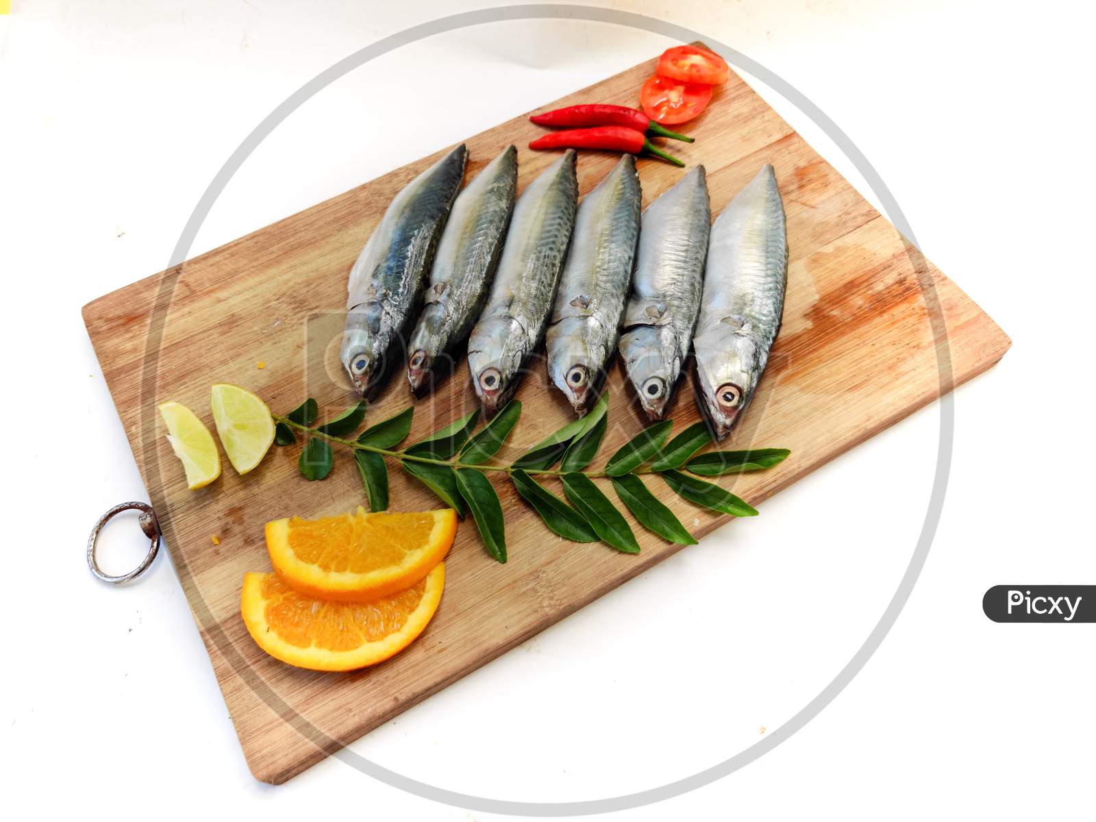 Image of Cleaned And Ready To Cook Fresh Fish Horse / Indian Mackerel Fish  Decorated With Herbs And Vegetables On A Wooden 