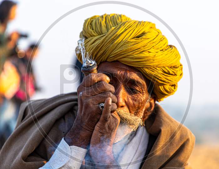 A Rajasthani Tribal Man Smoking Chillam At Pushkar Camel Festival.