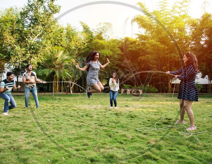 Indian Asian Young Friends Playing Jumping Rope, Enjoying Recreational Skipping Rope Game Outdoors
