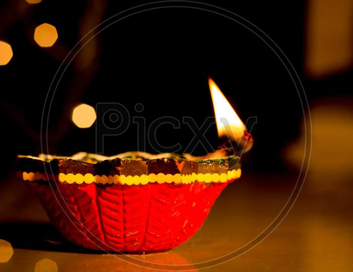 A Traditional Handmade Colorful Clay lamp lit against the Bokeh background for the Deepavali festival which is Celebrated across the Indian States.