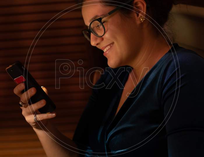 Happy Young Woman Looking Into Her Mobile Phone At Christmas.