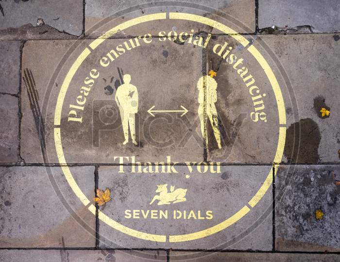 An Overhead Shot Of A Yellow Covid 19 Social Distancing Sign Painted On The Sidewalk In Covent Garden