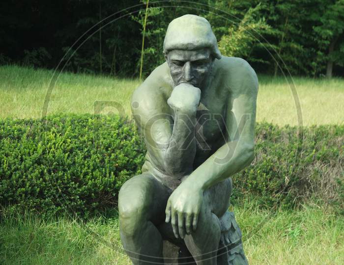 Green Statue Of Thinker Auguste Rodin, Setting Naked On A Rock