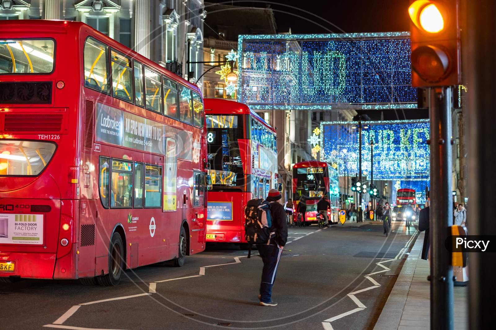 Red London Double Decker Buses With Oxford Street Illuminated Christmas Decorations In The Background