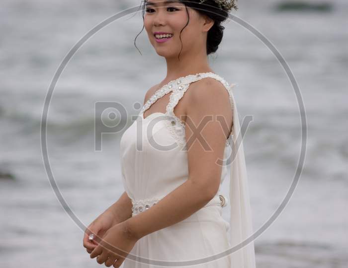 Chinese Bride In A White Wedding Dress Posing At The Beach